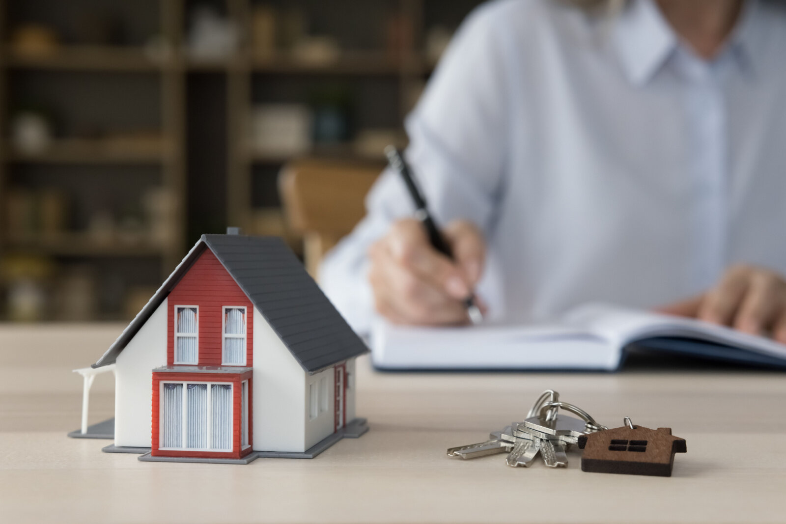 Keys from new home and tiny model of family house on work table of Preston Hollow community.