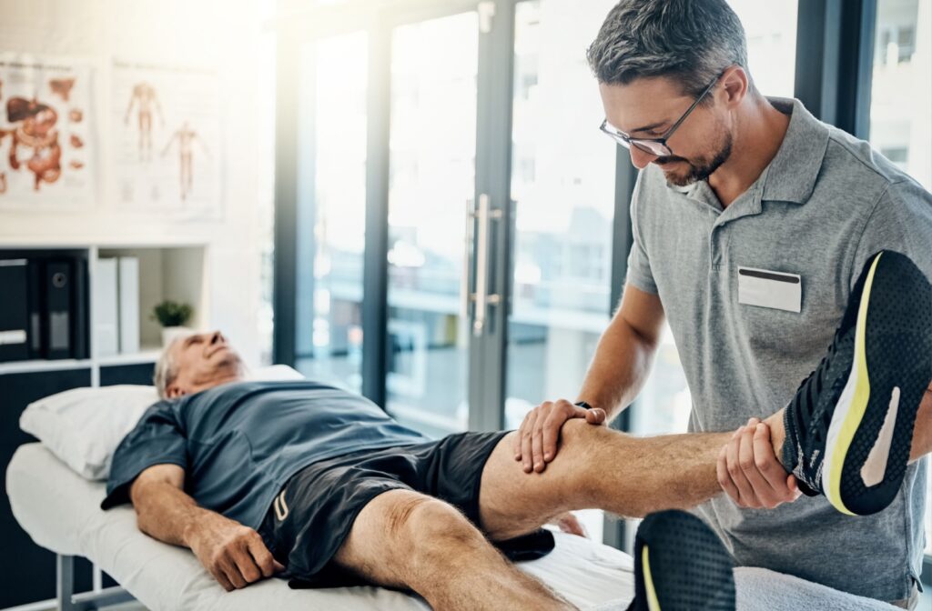 Man lying on a table while a therapist checks his leg.