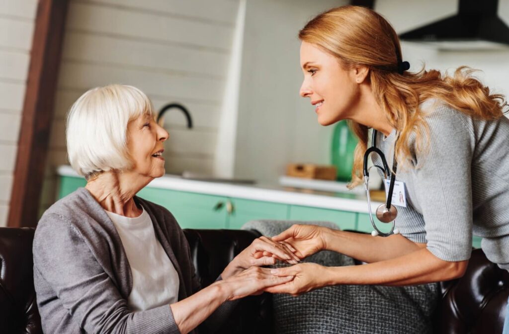 A helpful care worker attends to someone elderly with a compassionate smile.